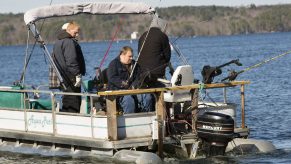 Men fishing off of a pontoon boat in a lake