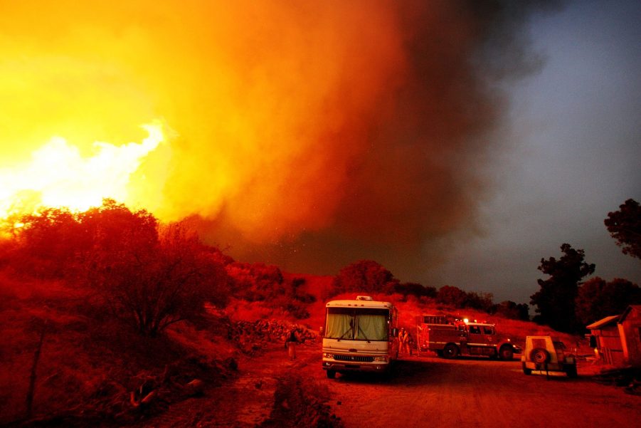 Firefighters protect an escaping RV from a wild fire.