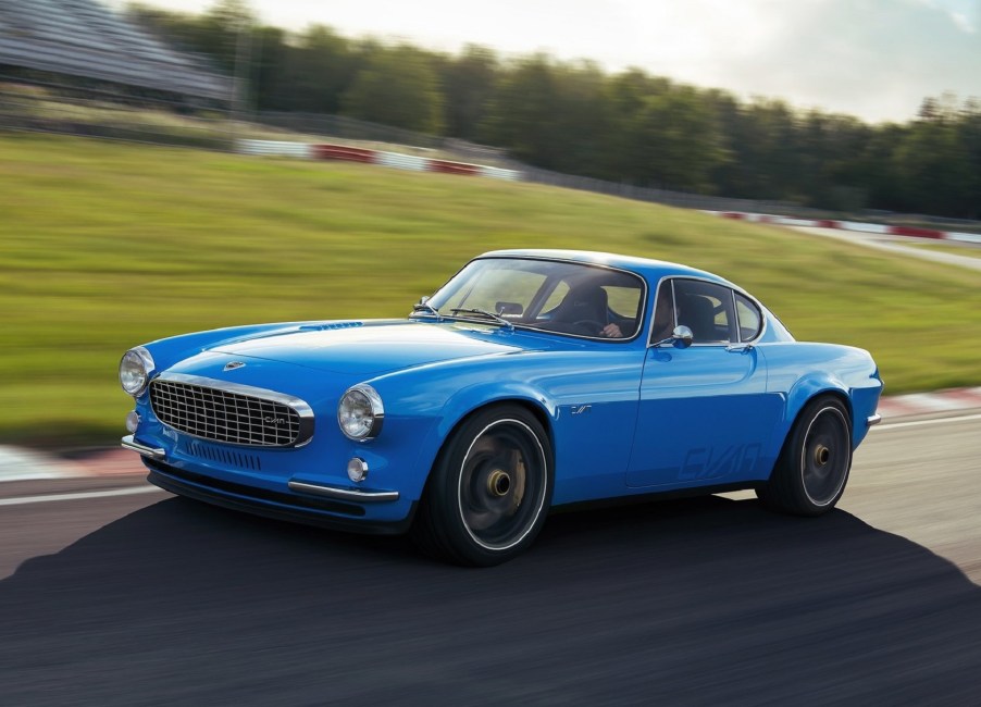 A blue Volvo P1800 Cyan restomod drives around a racetrack