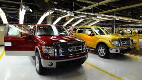 Two Ford F-150 trucks next to an assembly line