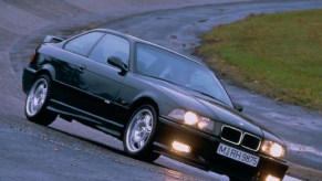 A green 1995 BMW E36 M3 GT drives around a wet racetrack