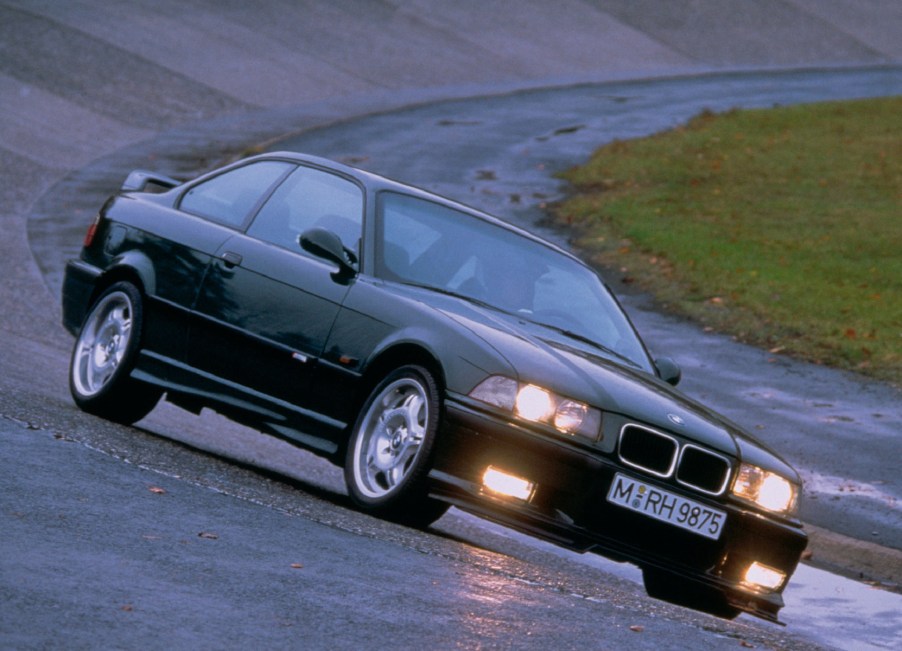 A green 1995 BMW E36 M3 GT drives around a wet racetrack