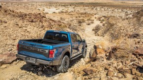 Blue Ford F-150 Raptor driving on gravel desert road