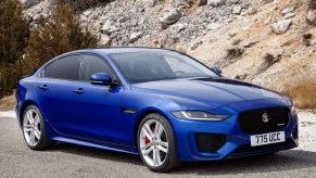 A blue 2020 Jaguar XE in front of a rocky hill