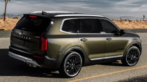 The rear 3/4 view of a green 2020 Kia Telluride on a desert road