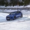 A blue 2021 Jaguar E-Pace driving on a snow-covered road.