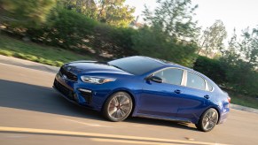 A blue 2021 Kia Forte displays its commuter car prowess while driving on the highway