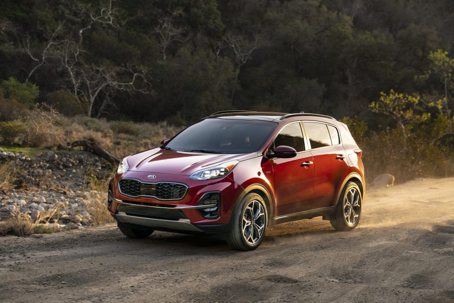 Red 2021 Kia Sportage drives down a dirt road in a mountainous environment