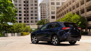 A blue 2021 Toyota RAV4 Prime facing away while parked in the middle of a city.