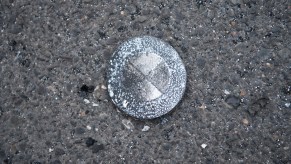 A burnt BMW emblem of a vehicle that fell down in a fire is lying in a parking lot of a supermarket