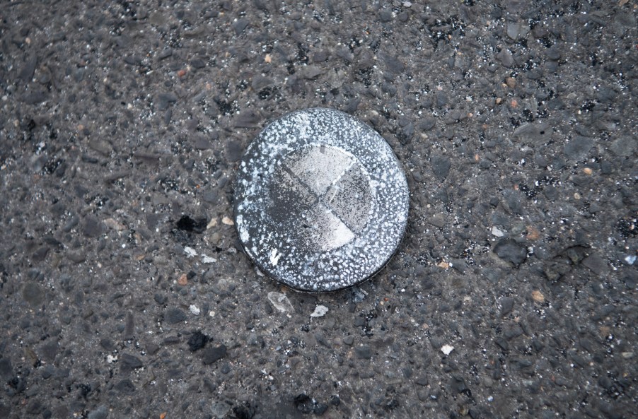 A burnt BMW emblem of a vehicle that fell down in a fire is lying in a parking lot of a supermarket