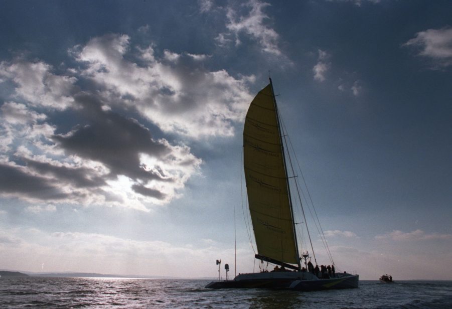 A catamaran sailboat seen sailing around sunset