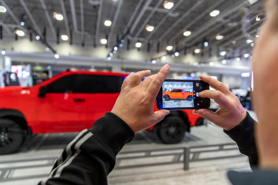 A man photographs a model 2019 Chevy Silverado pick up truck