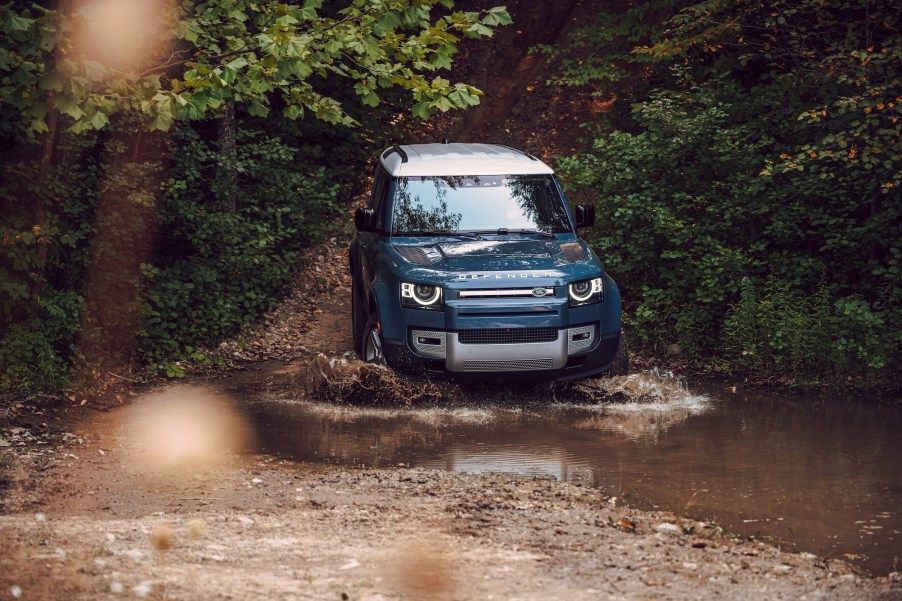 An image of a Land Rover Defender off-roading through some mud.