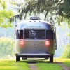 A gray Airstream Globetrotter camper off-road in the woods.