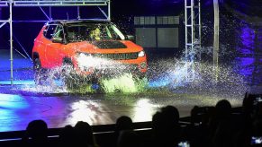 A red Jeep Compass puts its capability on display by driving into water