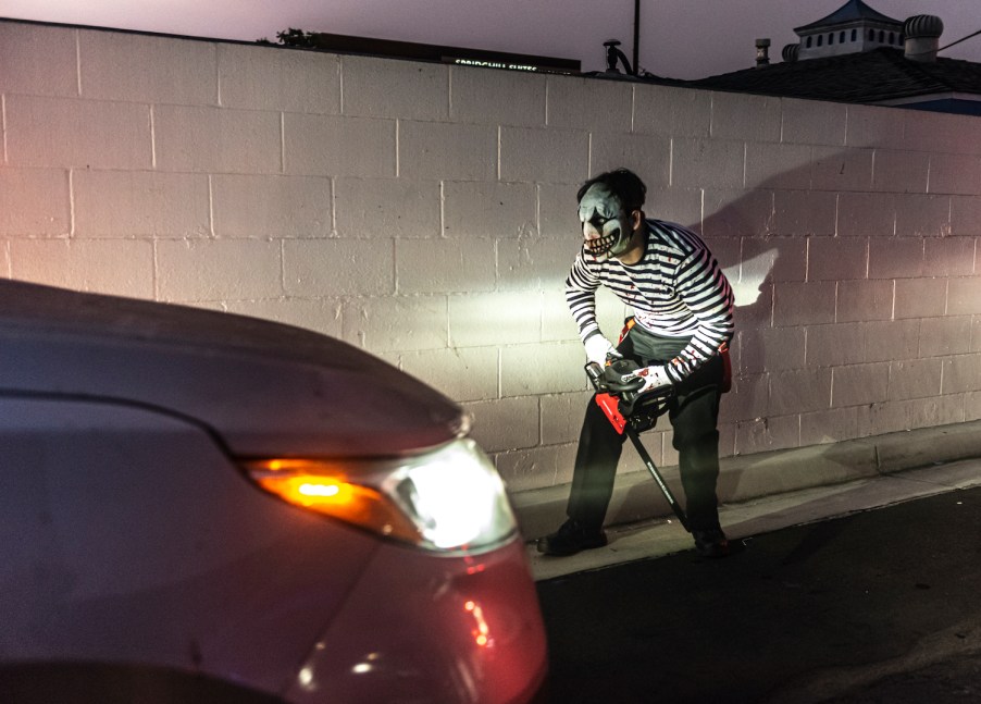 A person in Halloween costume in front of a car