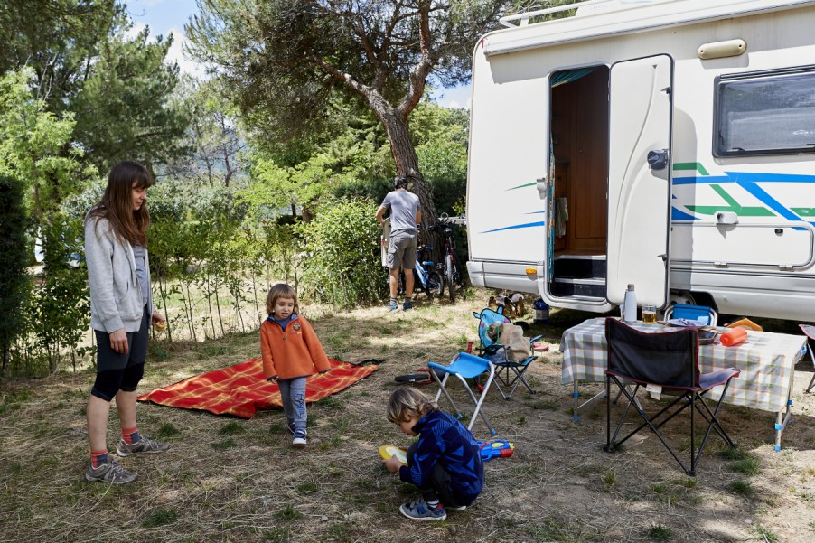 A family at a camp site with an RV in the background