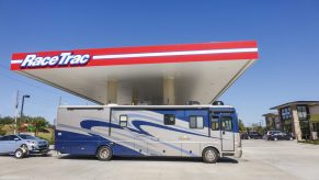 An RV towing a car refuels at a gas station