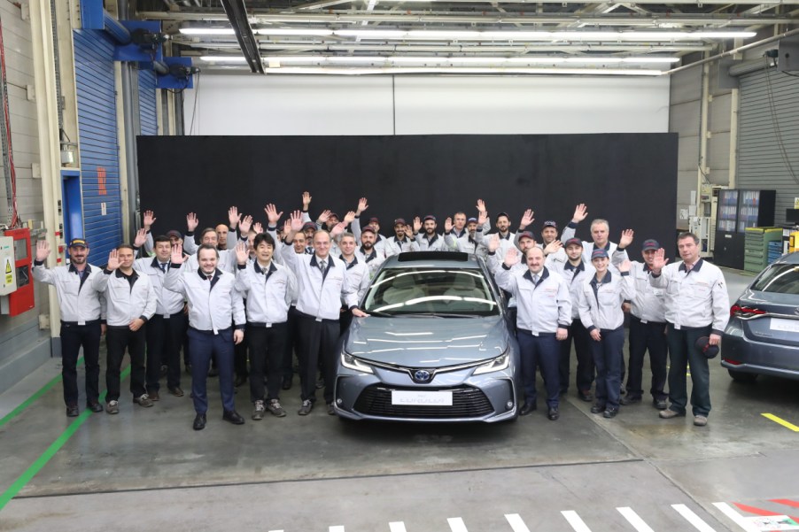 Toyota factory workers posing next to a new car