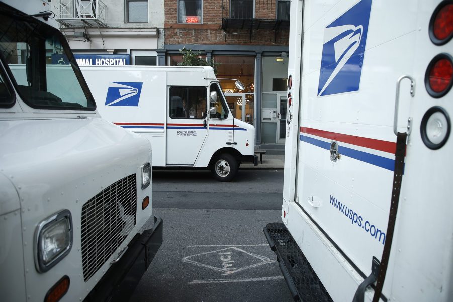 Three USPS trucks are awaiting loading and unloading.