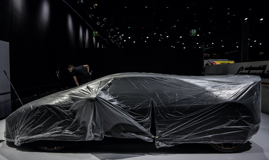 A Lamborghini is hidden under a cover on the grounds of the fair