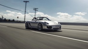 A silver 2011 Porsche Boxster Spyder drives down the road