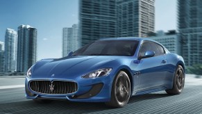 A blue 2013 Maserti GranTurismo Sport drives on a city road