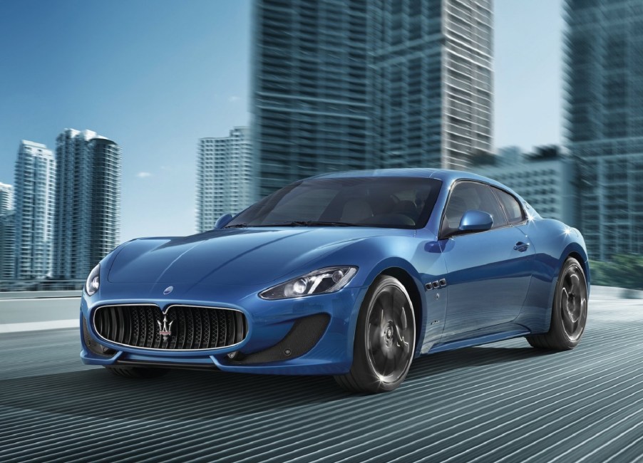 A blue 2013 Maserti GranTurismo Sport drives on a city road