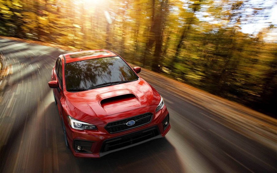 A red 2020 Subaru WRX Limited drives through a forest