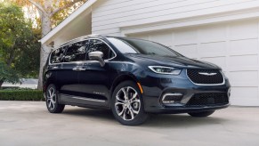 A blue 2021 Chrysler Pacifica parked in a driveway in front of a garage