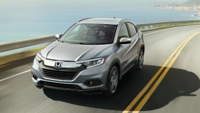 A silver 2021 Honda HR-V EX-L drives on an ocean-side road