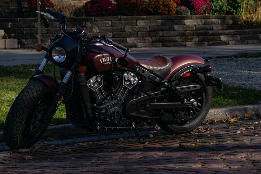 The front 3/4 view of a maroon 2021 Indian Scout Bobber on a shady street