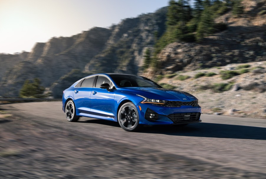 A blue 2021 Kia K5 driving on a highway