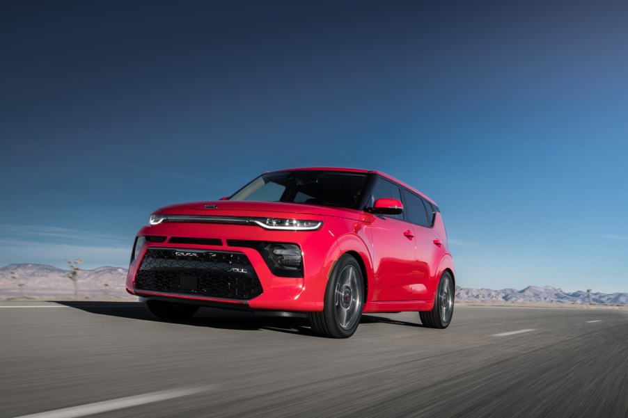 A red 2021 Kia Soul driving on a highway road