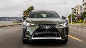 The front of a green 2021 Lexus UX on the road. Many drivers opt to buy a new Lexus because of its luxurious interior.