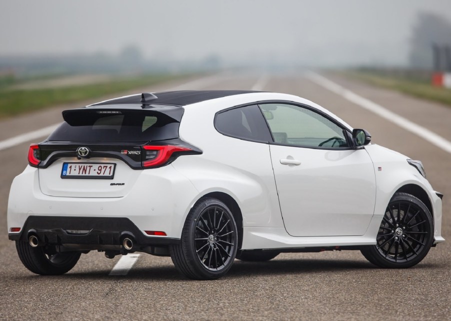 The rear 3/4 view of a white 2021 Toyota GR Yaris on a racetrack