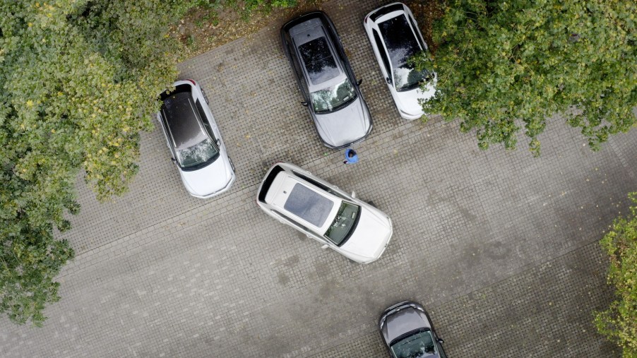 A 2021 Volkswagen Touareg using Park Assist with Remote Control to back into a space between two other SUVs