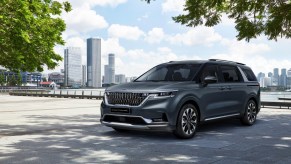 The 2022 Kia Sedona, aka 2022 Kia Carnival, parked on display with a cityscape in the background