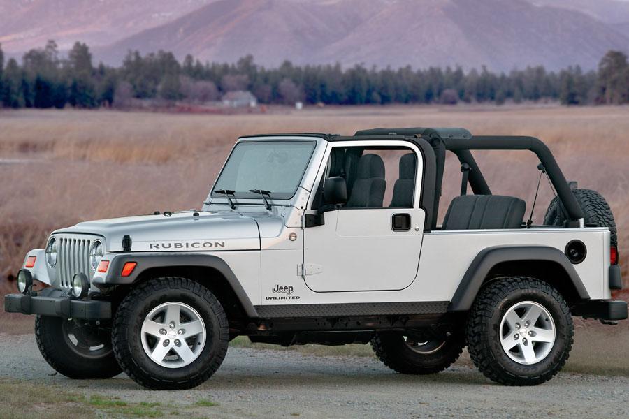 a light gray used Jeep Wrangler rubicon parked on a gravel road in the desert. 