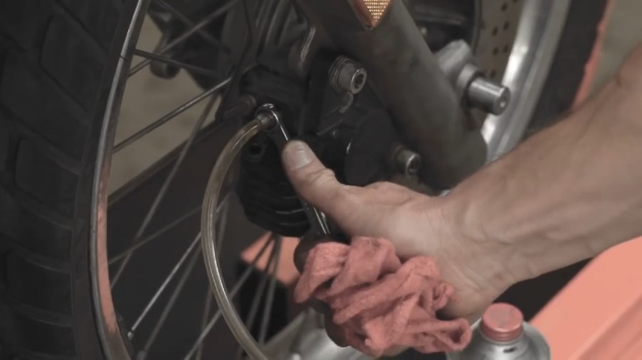 A mechanic bleeds a motorcycle's brakes