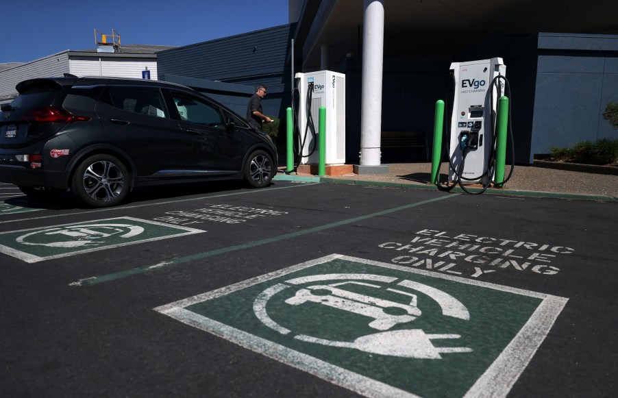 An electric car owner prepares to charge his car at an electric car charging station EV charging