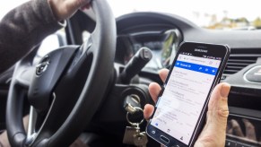 A person uses their phone while driving a car