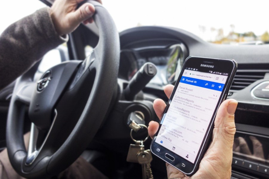 A person uses their phone while driving a car