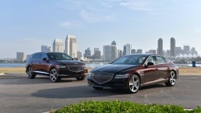 The Genesis GV80 and the Genesis G80 parked in front of a city skyline