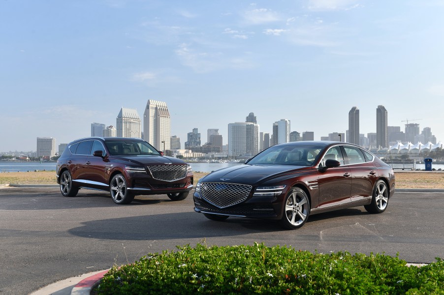 The Genesis GV80 and the Genesis G80 parked in front of a city skyline