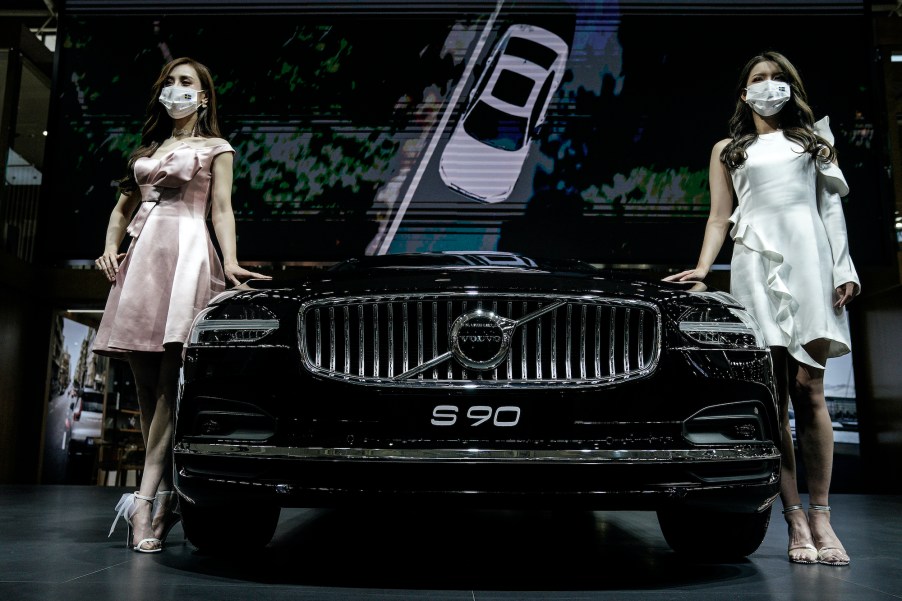 Models wear masks as a precaution while displaying a Volvo S90 in the Volvo stand during the 18th Central China International Auto Show