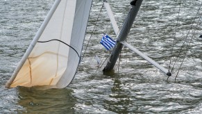 A sunken sailing yacht with a Greek flag on the mast can be seen in a harbor after the heavy autumn storm Ianos.