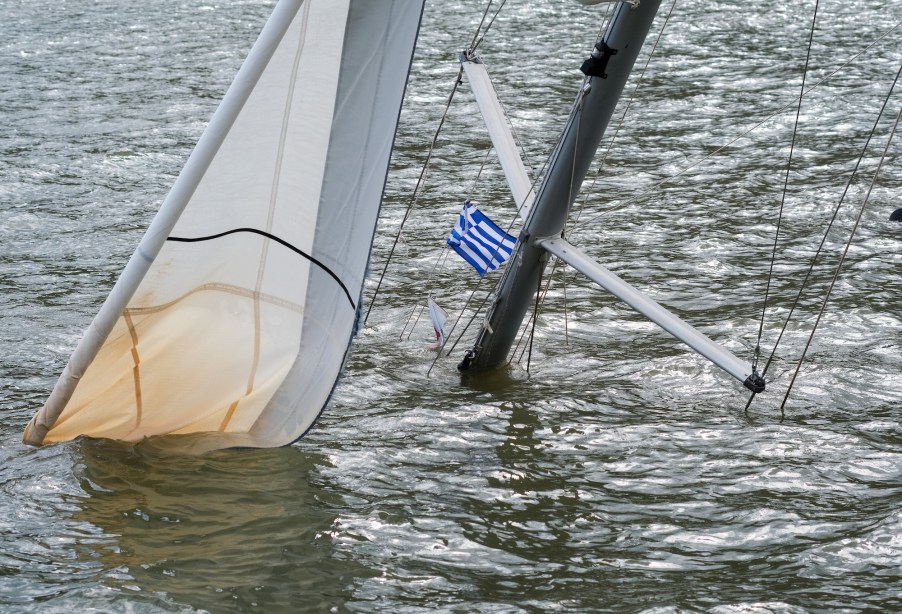 A sunken sailing yacht with a Greek flag on the mast can be seen in a harbor after the heavy autumn storm Ianos.