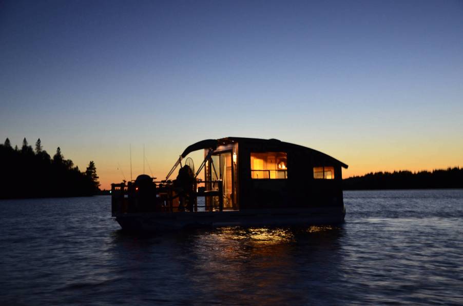 A Daigno Koroc P houseboat floats on the water at sunset.